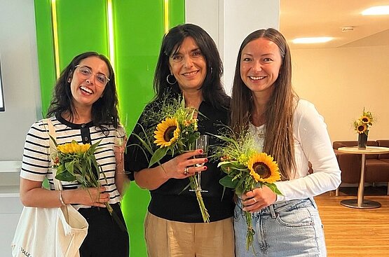 drei weibliche Absolventinnen mit Sonnenblume